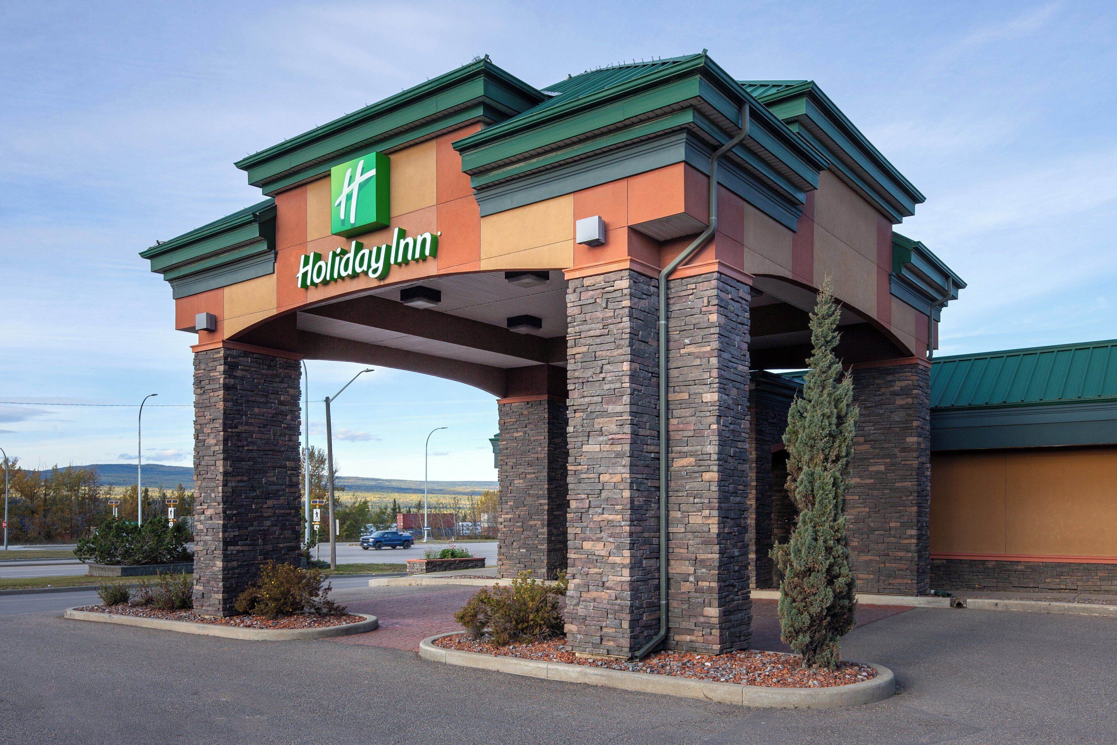 A Holiday Inn hotel entrance with a stone facade and green roof.