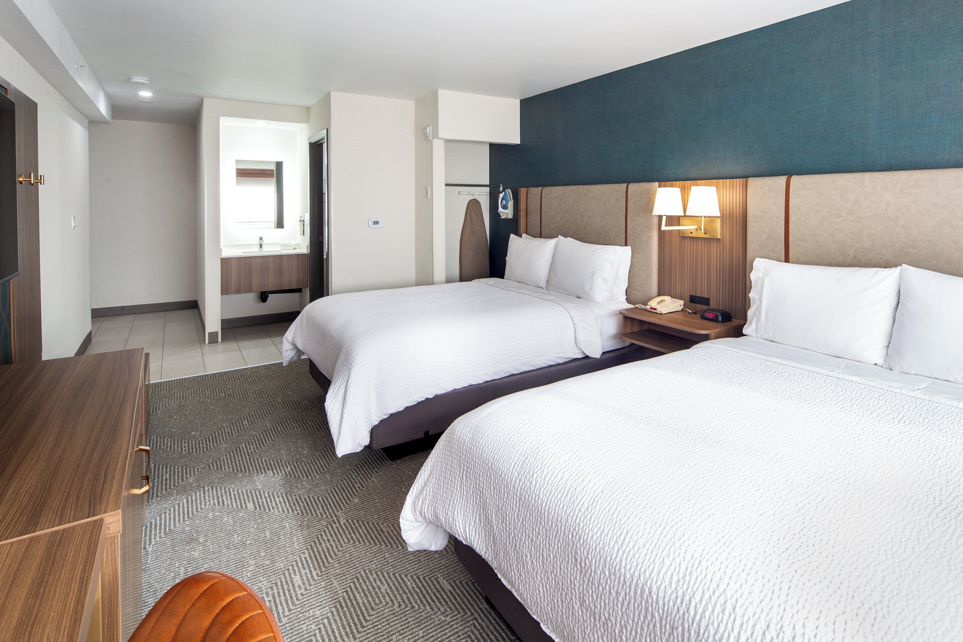 A hotel room with two beds, a desk, and a chair.