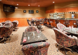 A hotel room with a bar area, multiple seating arrangements, and a television mounted on the wall. - Holiday Inn Hinton by IHG (Hinton)
