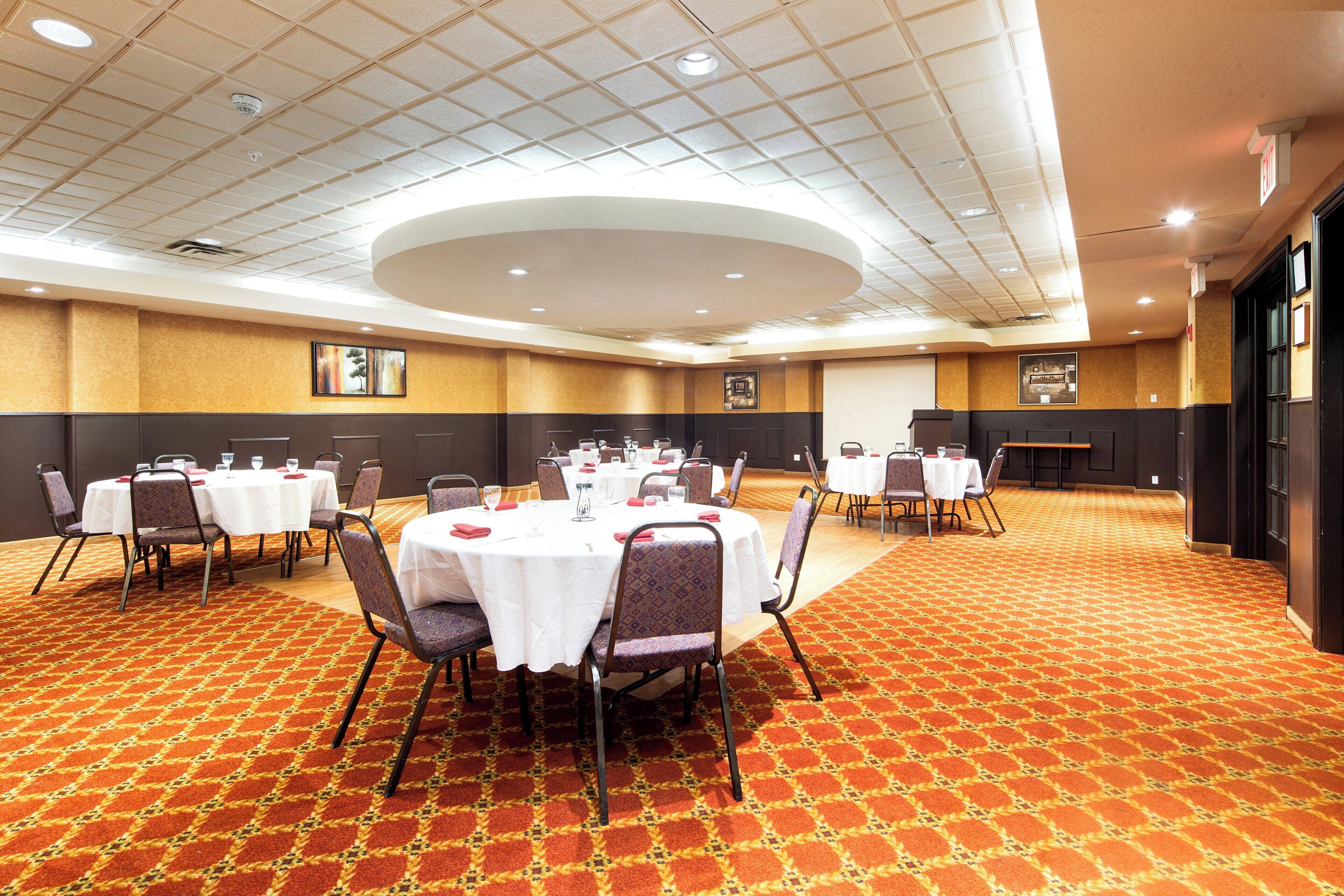 A conference room with round tables, chairs, and a patterned carpet.
