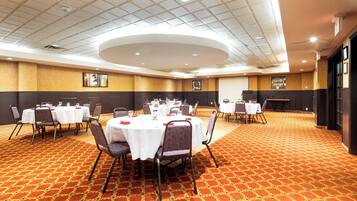 A conference room with round tables, chairs, and a patterned carpet.