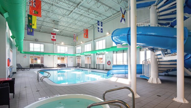 An indoor swimming pool with a hot tub, lounge area, and a water slide. - Holiday Inn Hinton by IHG (Hinton)