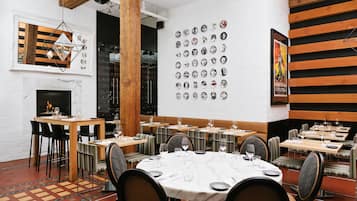A restaurant with round tables, chairs, and a wall of vintage posters.