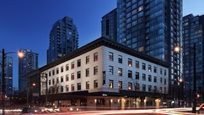 A multi-story hotel with a classic facade, located in a cityscape with modern high-rise buildings. - Moda Hotel (Vancouver)