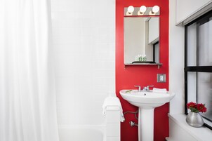 A bathroom with a white sink, red accent wall, and a mirror above it.