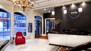 A hotel lobby with a reception desk, a chandelier, and a red chair. - Moda Hotel (Vancouver)