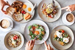 Una escena de desayuno con diferentes platos, entre ellos tostadas, huevos y ensaladas.