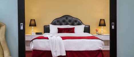 A hotel room with a large bed, two bedside tables, a chair, and a red carpet.