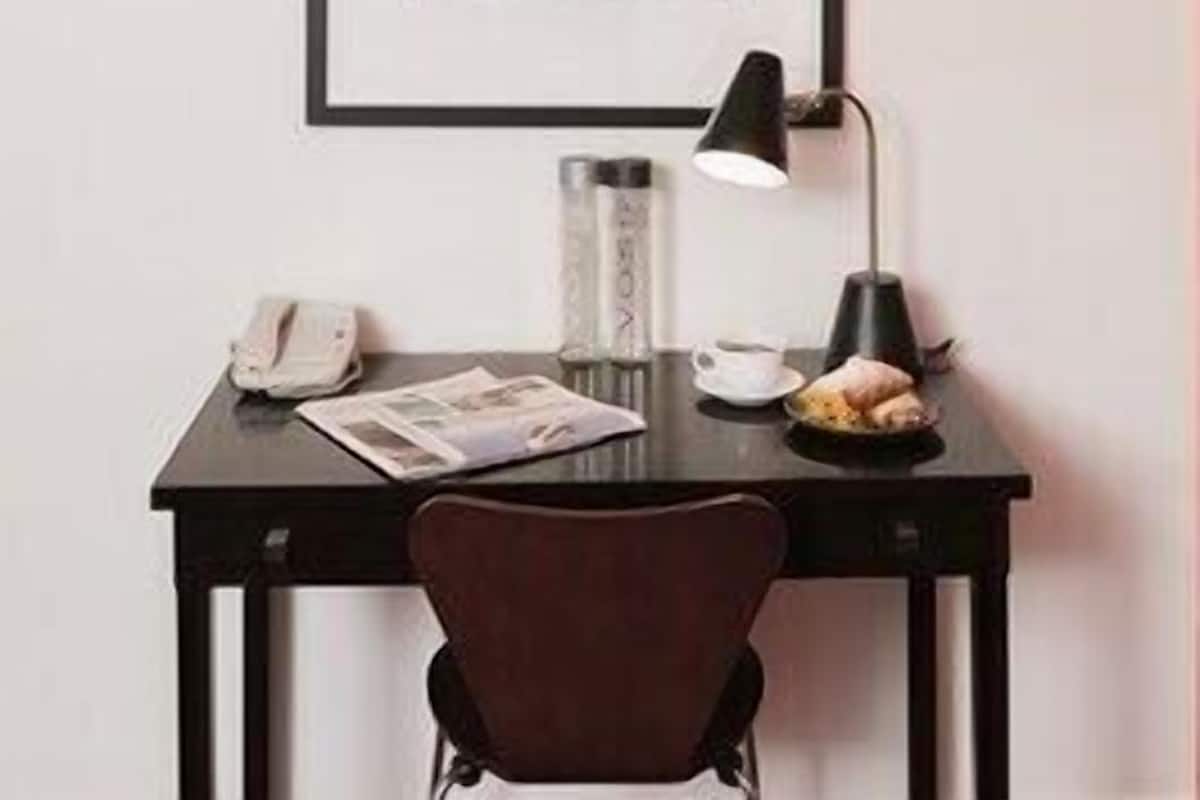 A desk with a framed picture, a lamp, a phone, and a chair.
