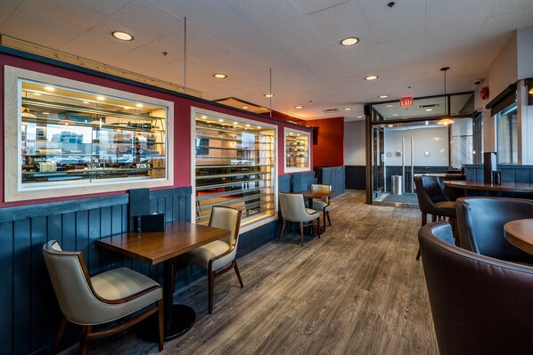 A restaurant interior with wooden flooring, booths, and a bar area with glass display cases.