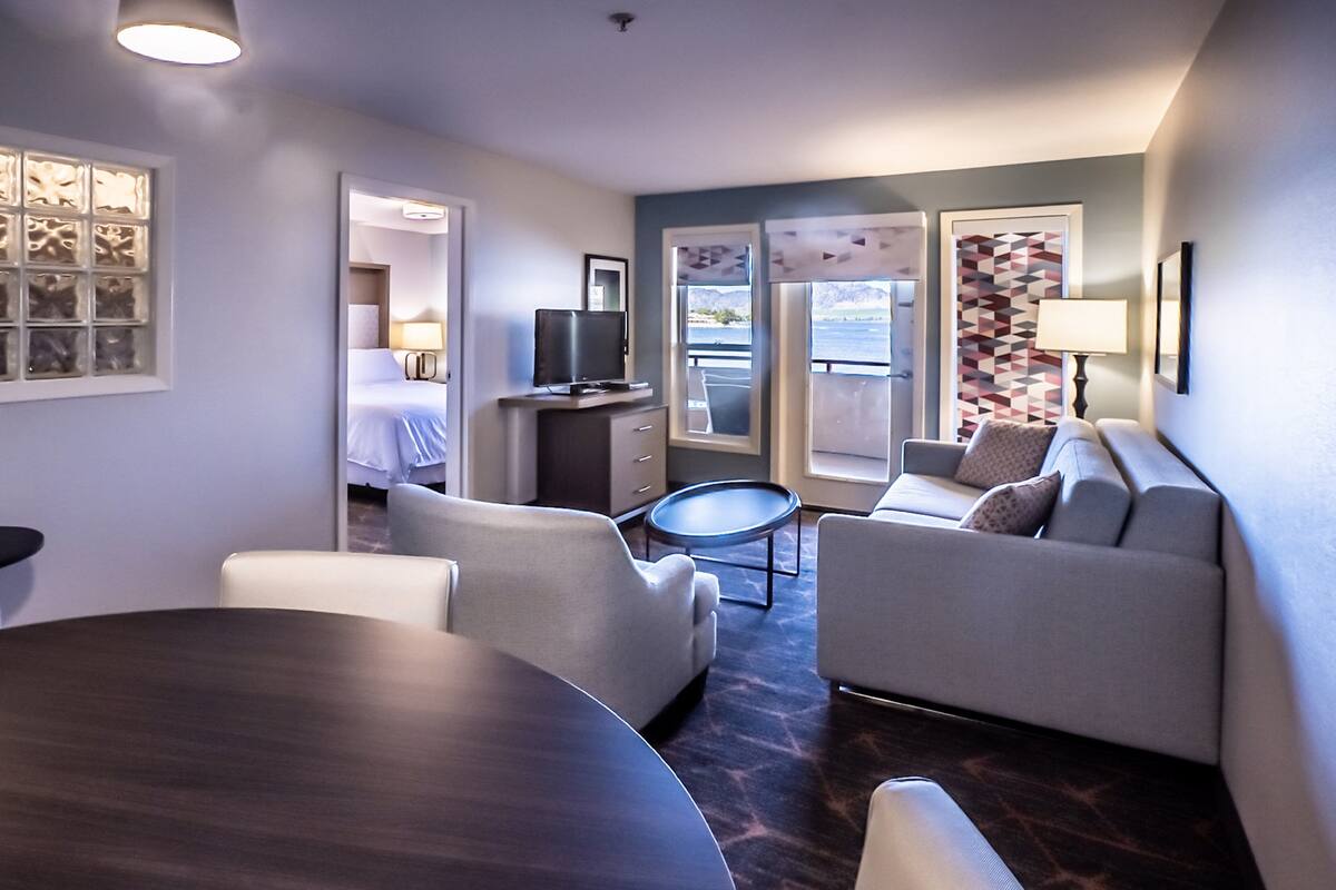 Una habitación de hotel moderna con una cama, un sofá, una mesa de comedor y un televisor.
