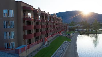 A multi-story hotel with balconies, a grassy area, and a body of water.