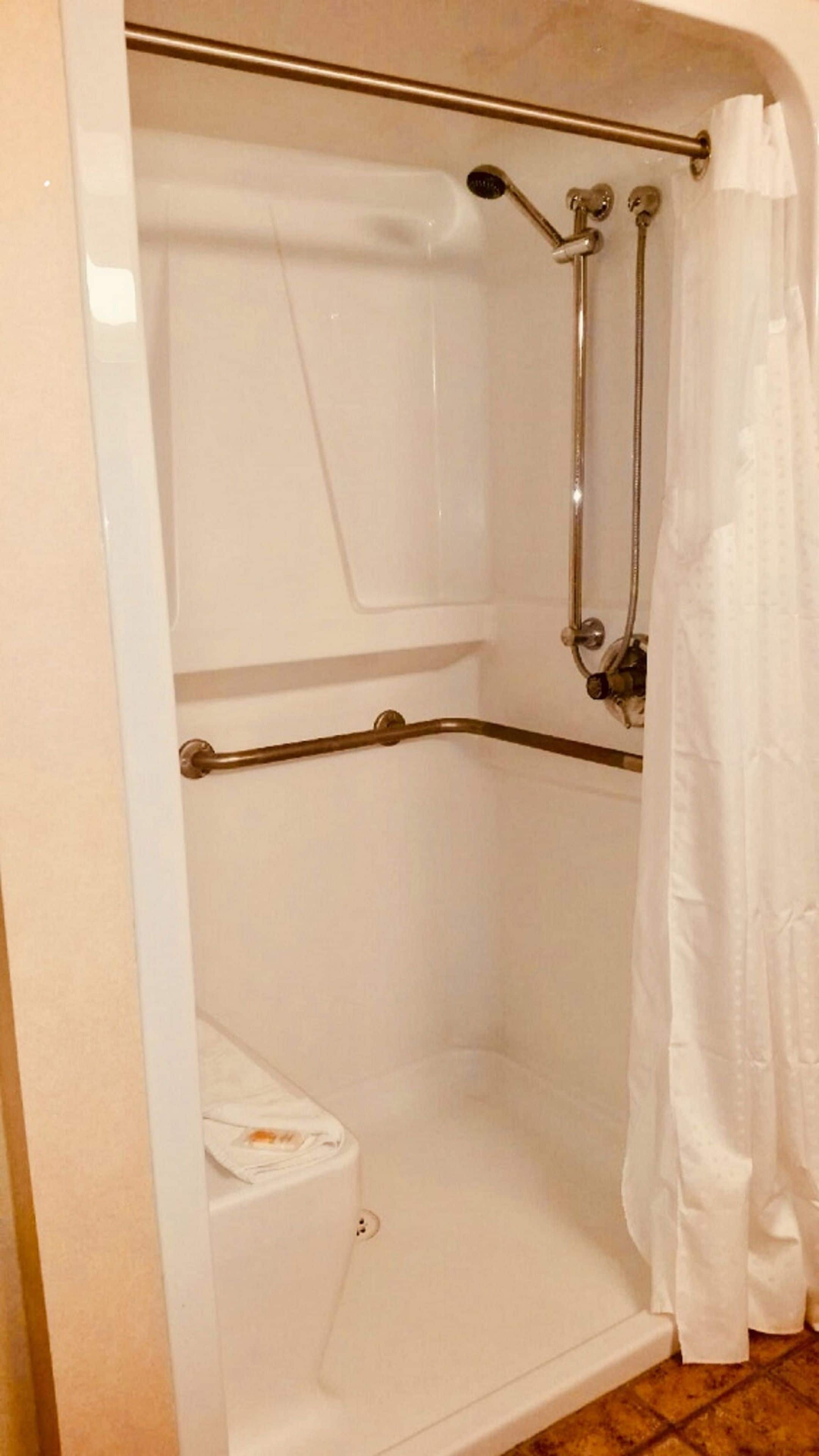 A shower with a glass door, a handheld showerhead, and a towel rack.