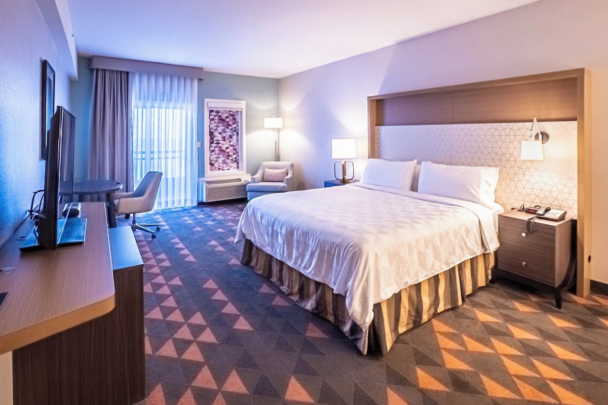 Une chambre d’hôtel équipée d’un lit, d’un bureau, d’une chaise et d’un téléviseur.