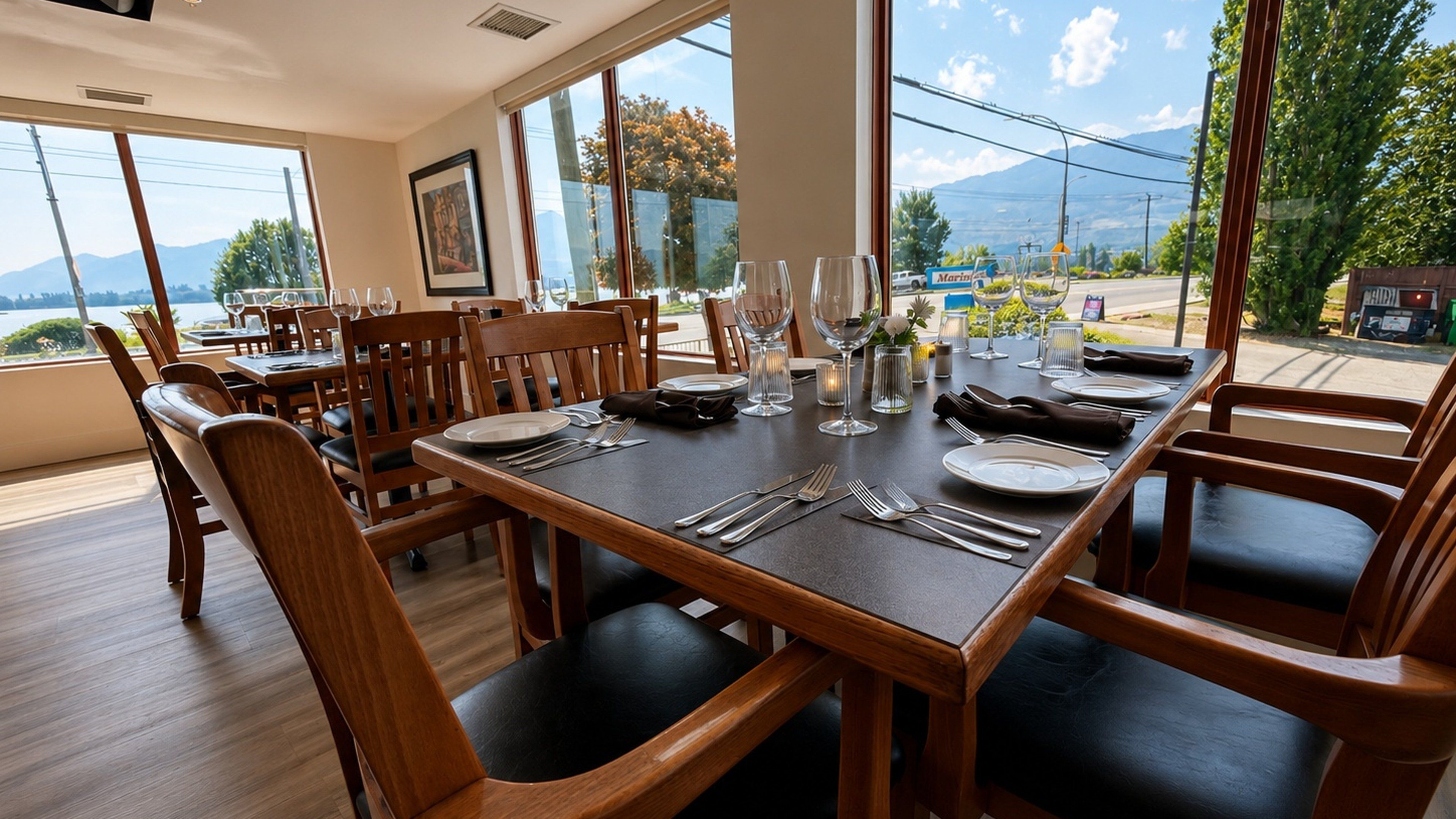 Un coin repas avec une table dressée pour quatre personnes, des chaises en bois et une vue sur l’extérieur.
