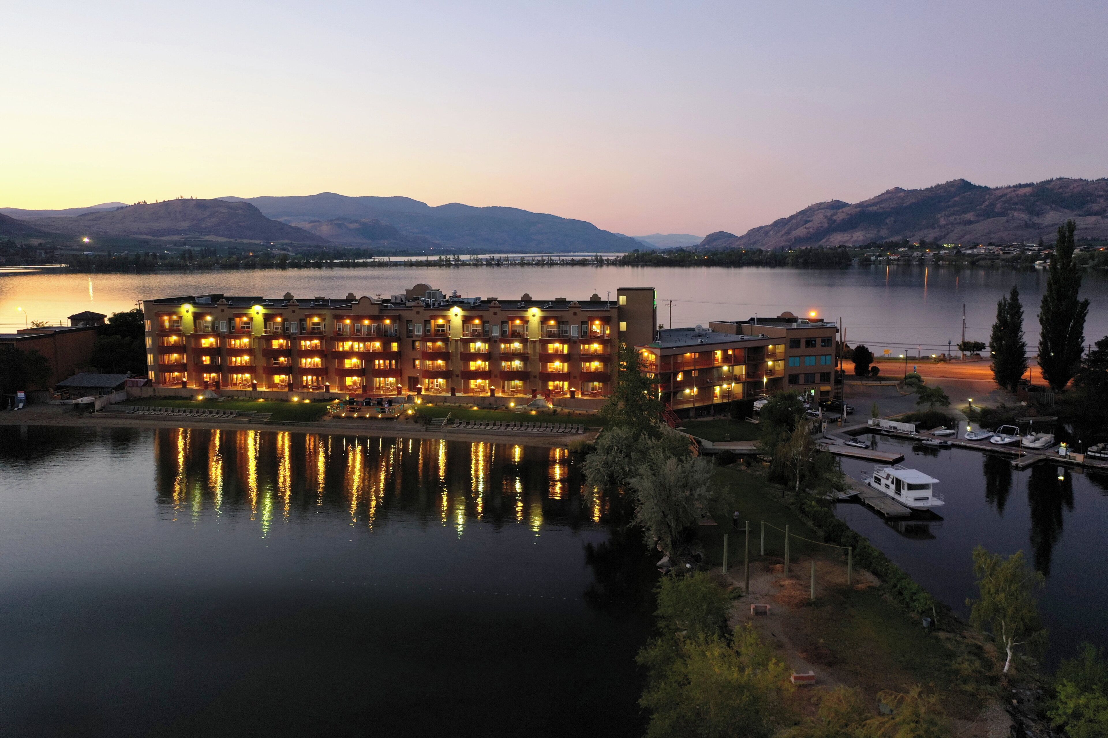 A multi-story hotel with a waterfront view, docked boats, and a calm lake.