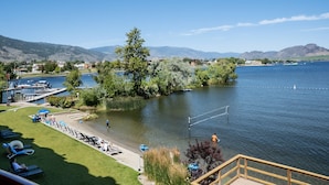 A lakeside view with a dock, boats, and a grassy area with lounge chairs.