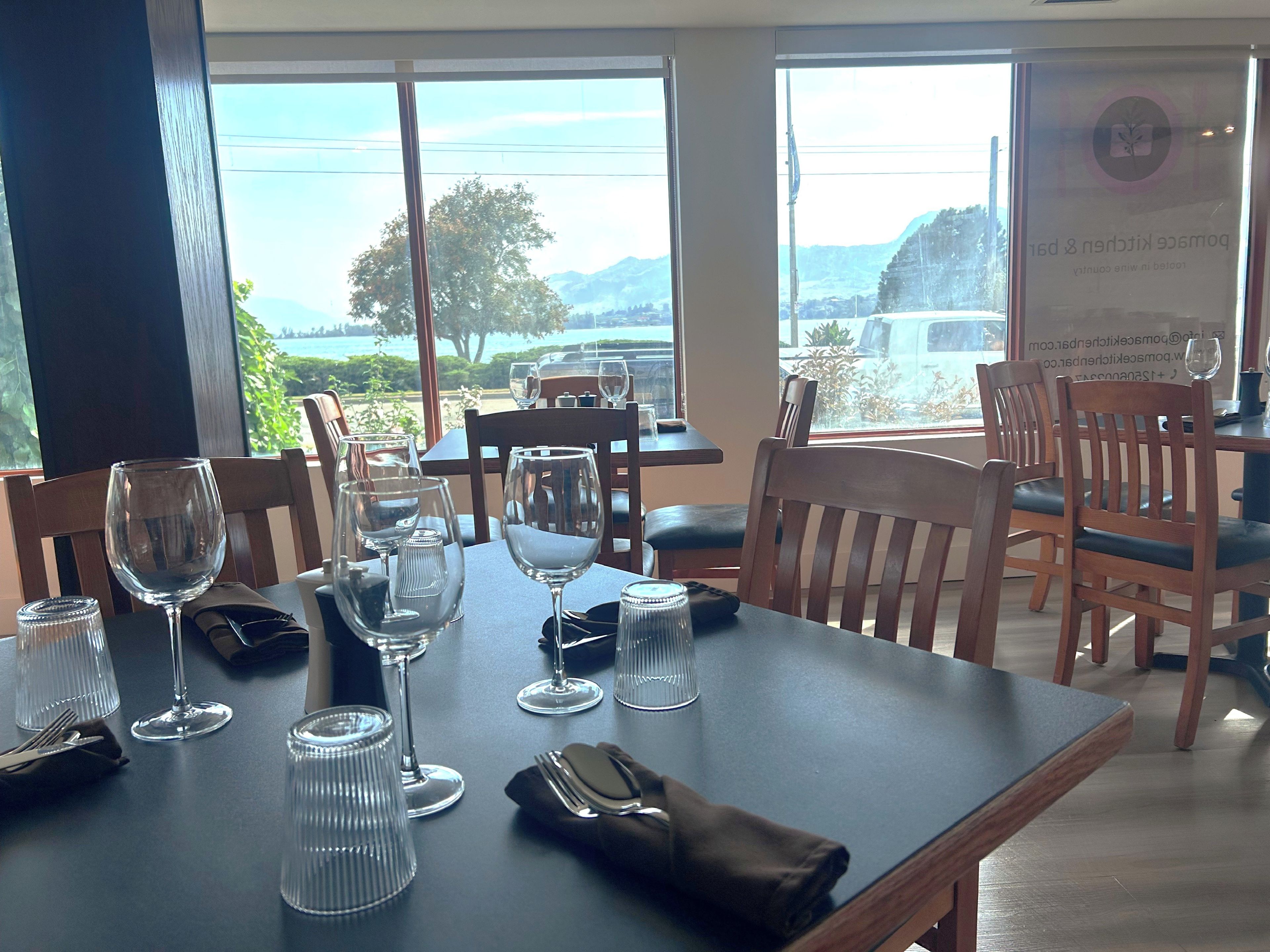 Un comedor con mesas dispuestas para una comida, sillas y vistas al exterior.