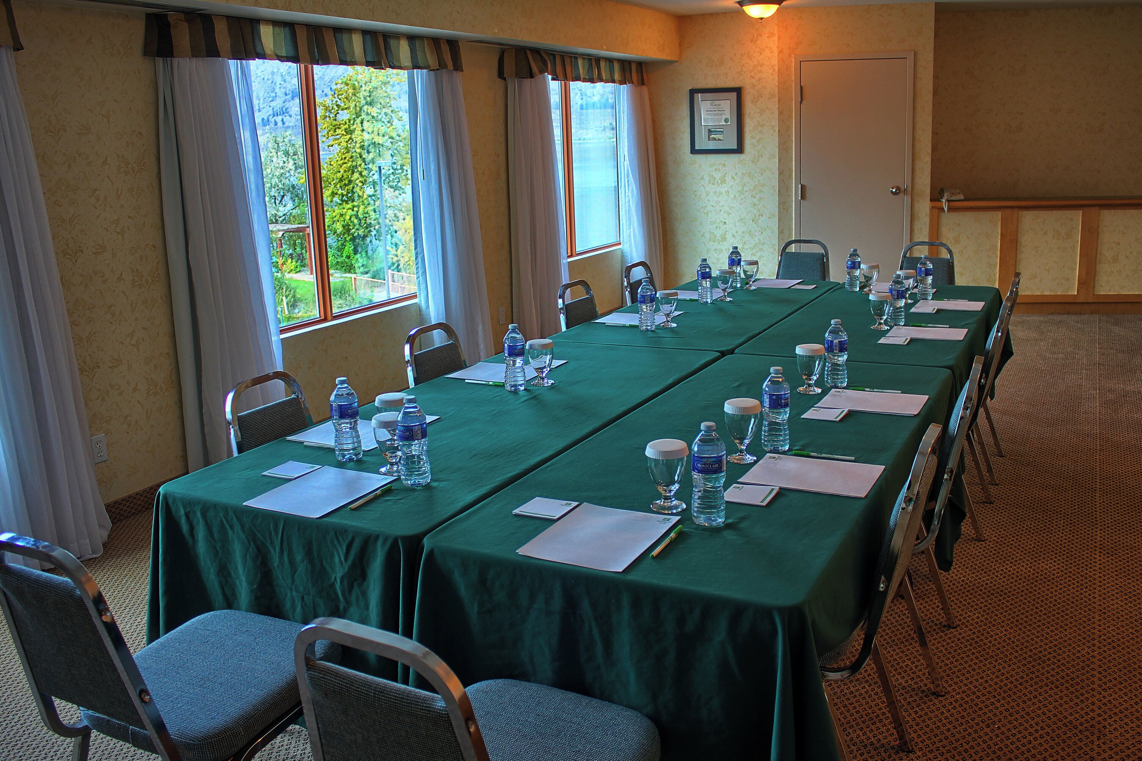 A conference room with a long table set for meetings, equipped with water bottles and glasses, and chairs arranged around it.