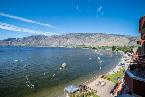 Une vue sur le lac, avec des bateaux, des nageurs et une chaîne de montagnes en arrière-plan.