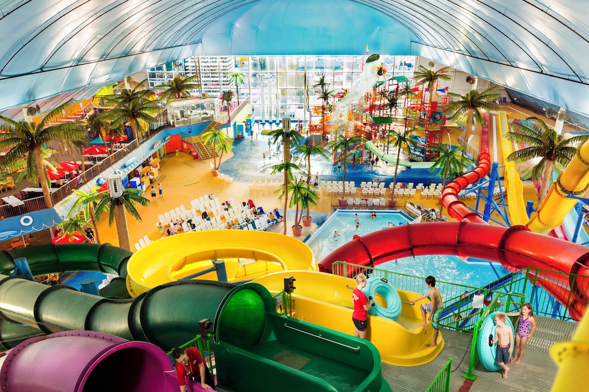 Ein Wasserpark mit mehreren Rutschen und Pools, Innenbereichen zum Verweilen und einem überdachten Bereich mit Blick auf die Stadtlandschaft.