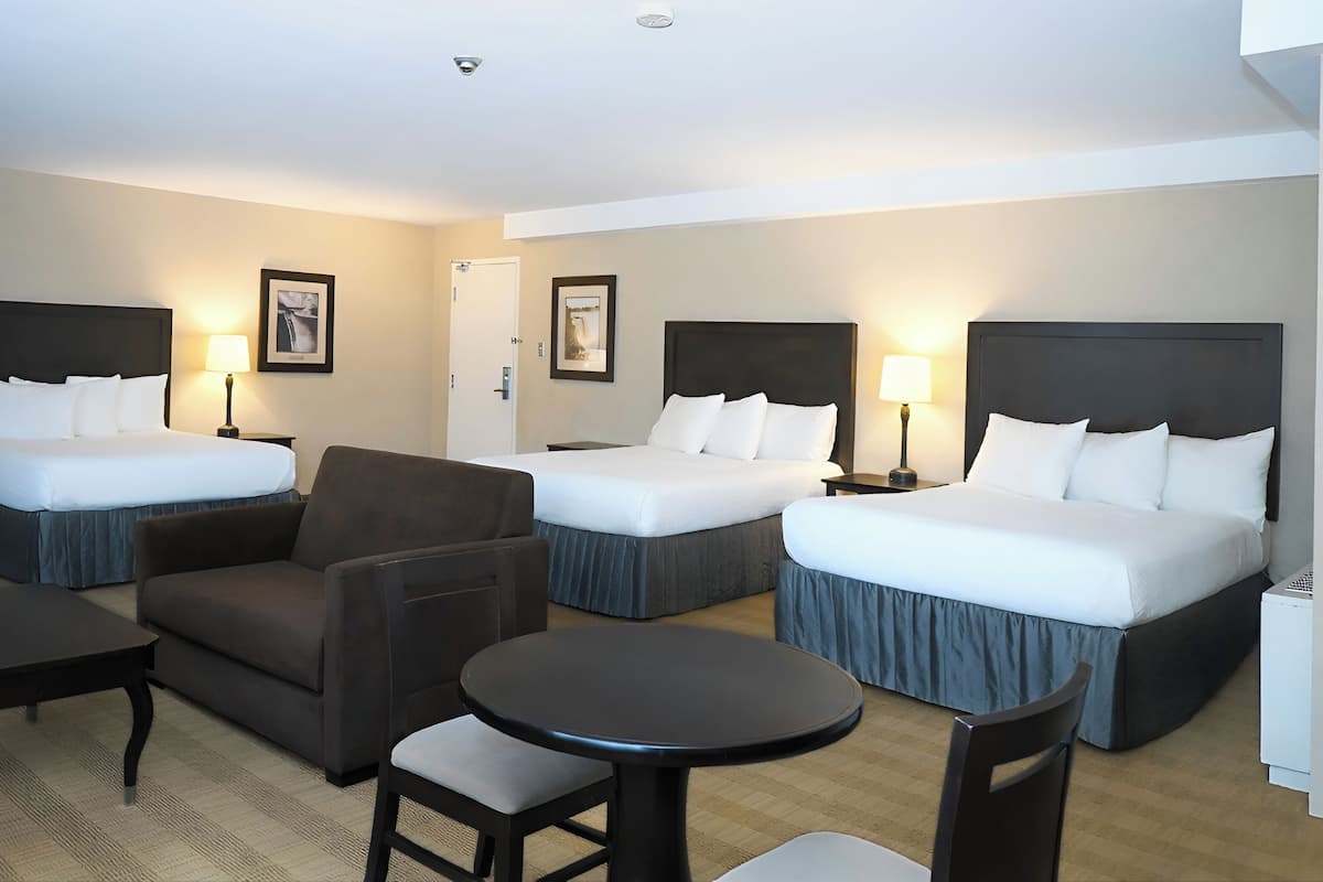 Ein Hotelzimmer mit zwei Betten, einem Sofa, einem kleinen Tisch und einem Stuhl.