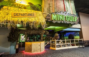 A mini-golf area with a sign labeled "Departures" and a neon sign for "Mini Golf".