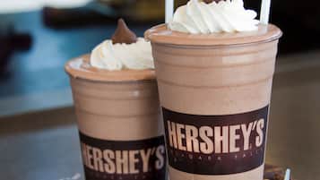 Two cups of chocolate milkshakes with whipped cream and a chocolate piece on top, labeled 'Hershey's'.