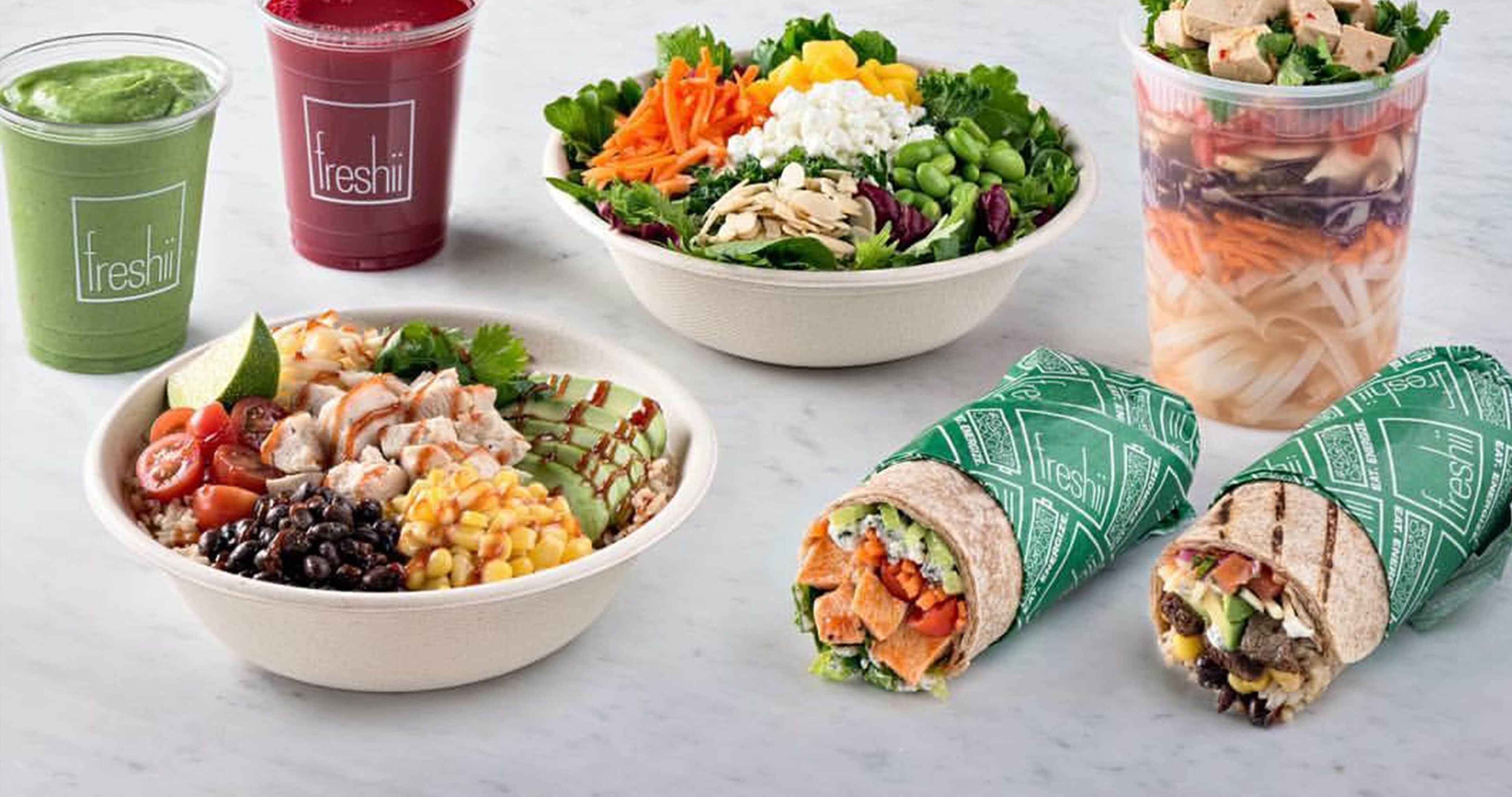 Forskellige friske salater, smoothies og wraps, der indikerer et fokus på sund mad.