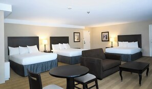Une chambre d’hôtel avec deux lits, un canapé, une petite table et une chaise.