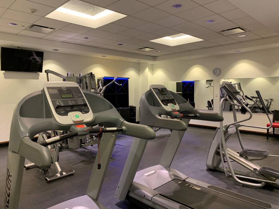 A gym with treadmills, a stair climber, and a mirrored wall.