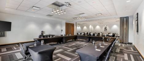 A conference room with a long table, multiple chairs, and a projector screen.