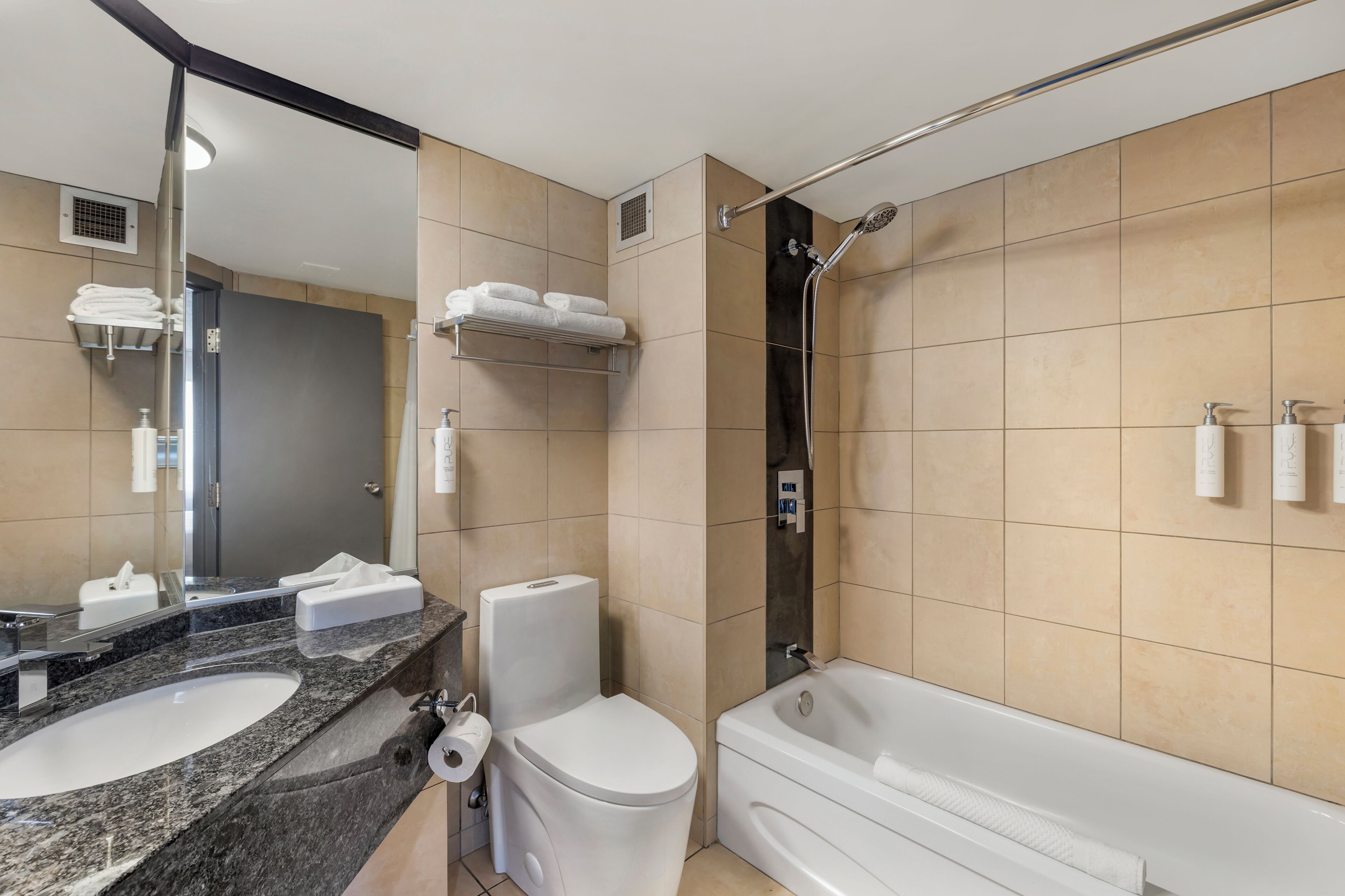 A modern bathroom with a sink, toilet, and bathtub. There are towels and toiletries on the counter.