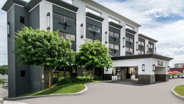 A modern hotel building with a flat roof, large windows, and a well-maintained lawn. - Hotel Quartier, an Ascend Collection Hotel (Québec City)