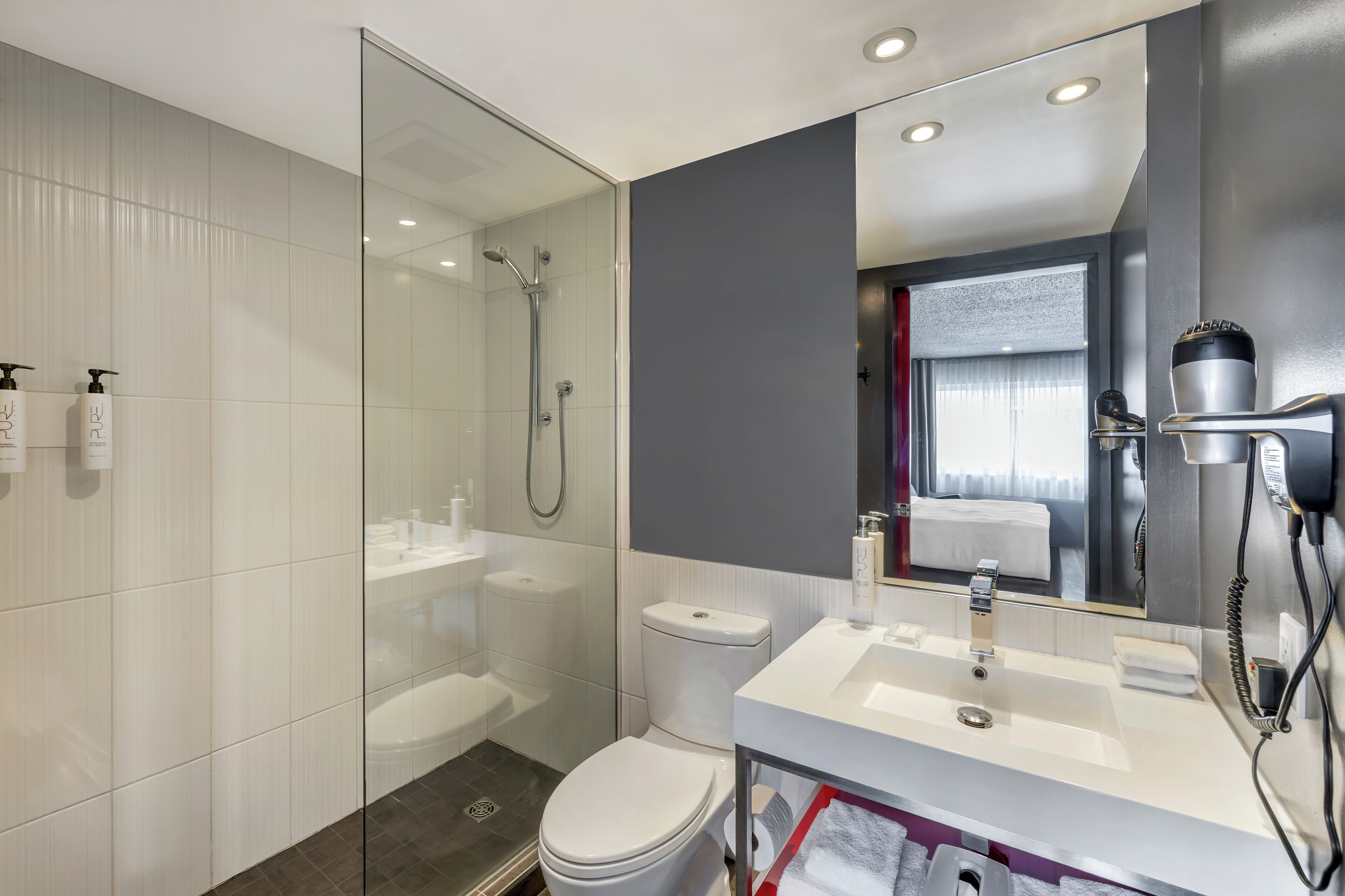 A modern bathroom with a glass shower enclosure, a white sink, and a toilet.