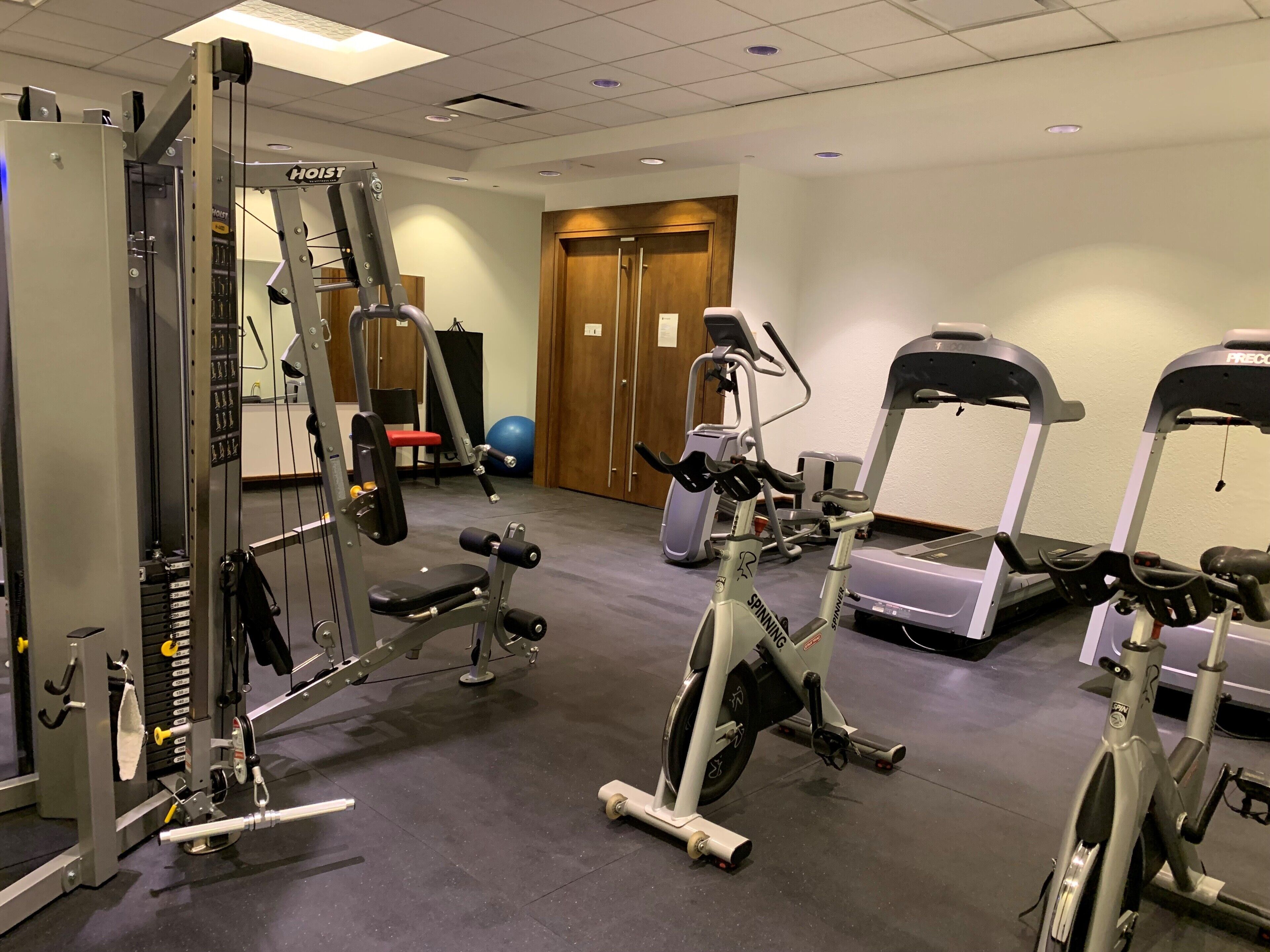 A gym with various exercise equipment including a Smith machine, elliptical, and treadmills.