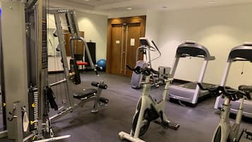 A gym with various exercise equipment including a Smith machine, elliptical, and treadmills.
