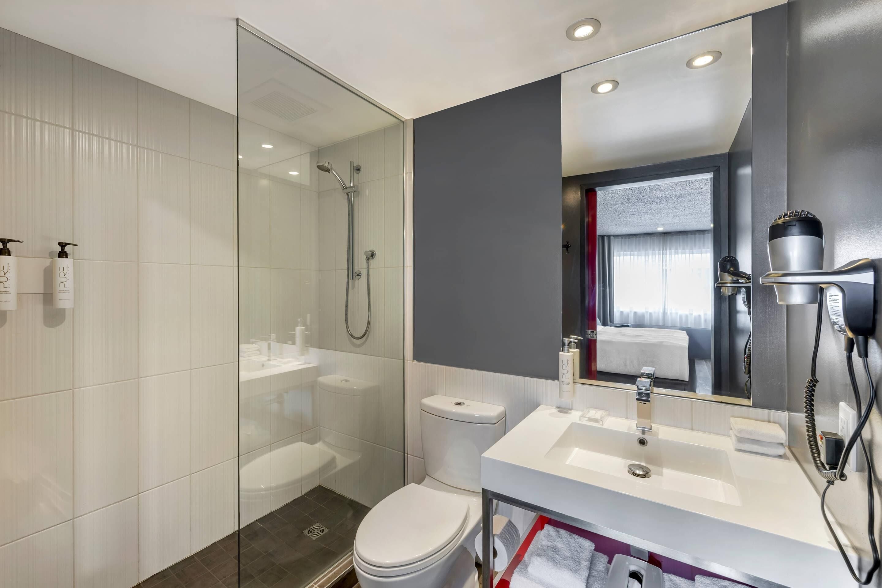 A modern bathroom with a glass shower enclosure, a white sink, and a toilet.