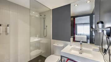 A modern bathroom with a glass shower enclosure, a white sink, and a toilet.