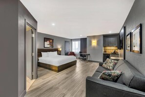 A modern hotel room with a large bed, a sofa, a desk, and a kitchenette. - Hotel Quartier, an Ascend Collection Hotel (Québec City)