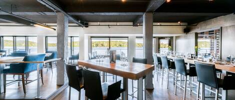 A spacious dining area with high ceilings, exposed beams, and large windows offering views of the outdoors.