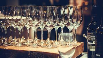 A row of empty wine glasses on a wooden table with a bottle of wine.