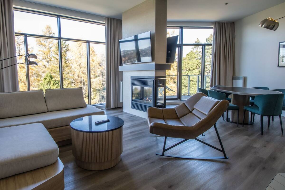 A modern living room with a sofa, a coffee table, a TV, and a fireplace.