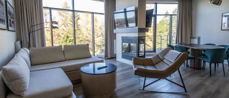 A modern living room with a sofa, a coffee table, a TV, and a fireplace.