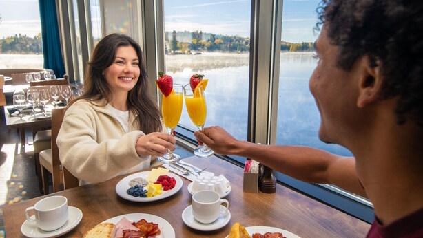 A breakfast setting with a table, plates of food, and two glasses of orange juice with strawberries. - Esterel Resort (Estérel)
