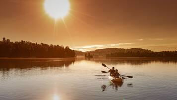 A calm lake at sunset with a kayak and two people paddling.