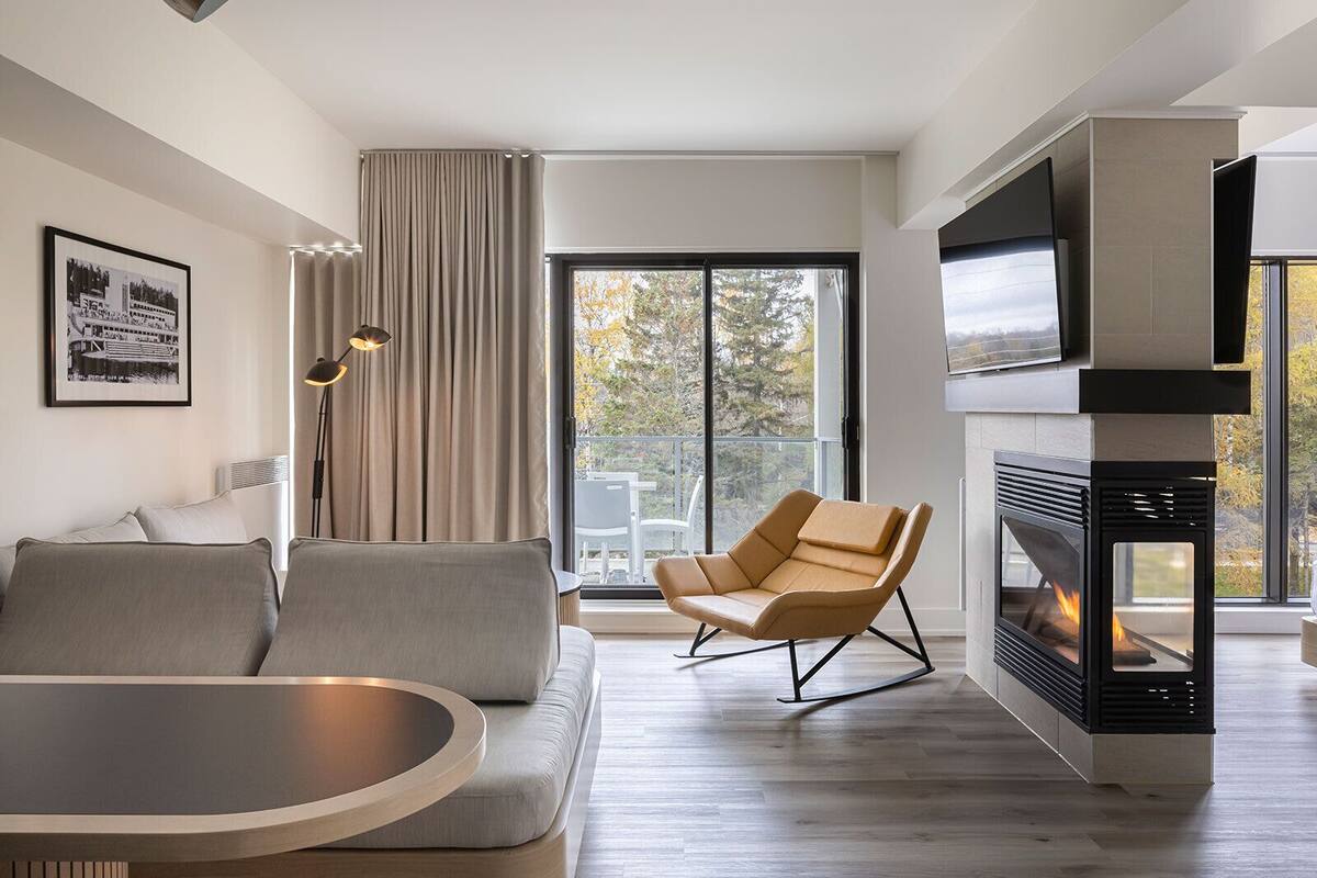 A modern living room with a sofa, a dining table, a TV, and a fireplace.