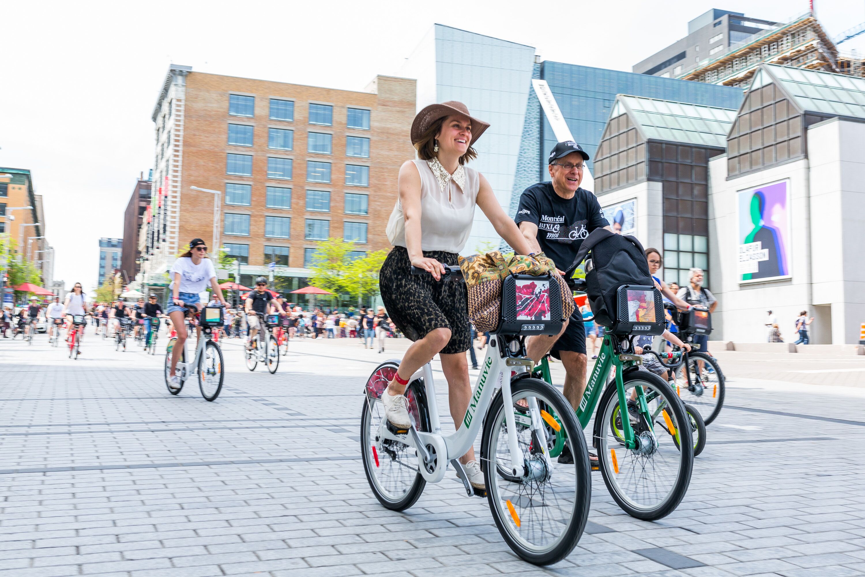A group of people riding bicycles in an urban setting with modern buildings in the background.