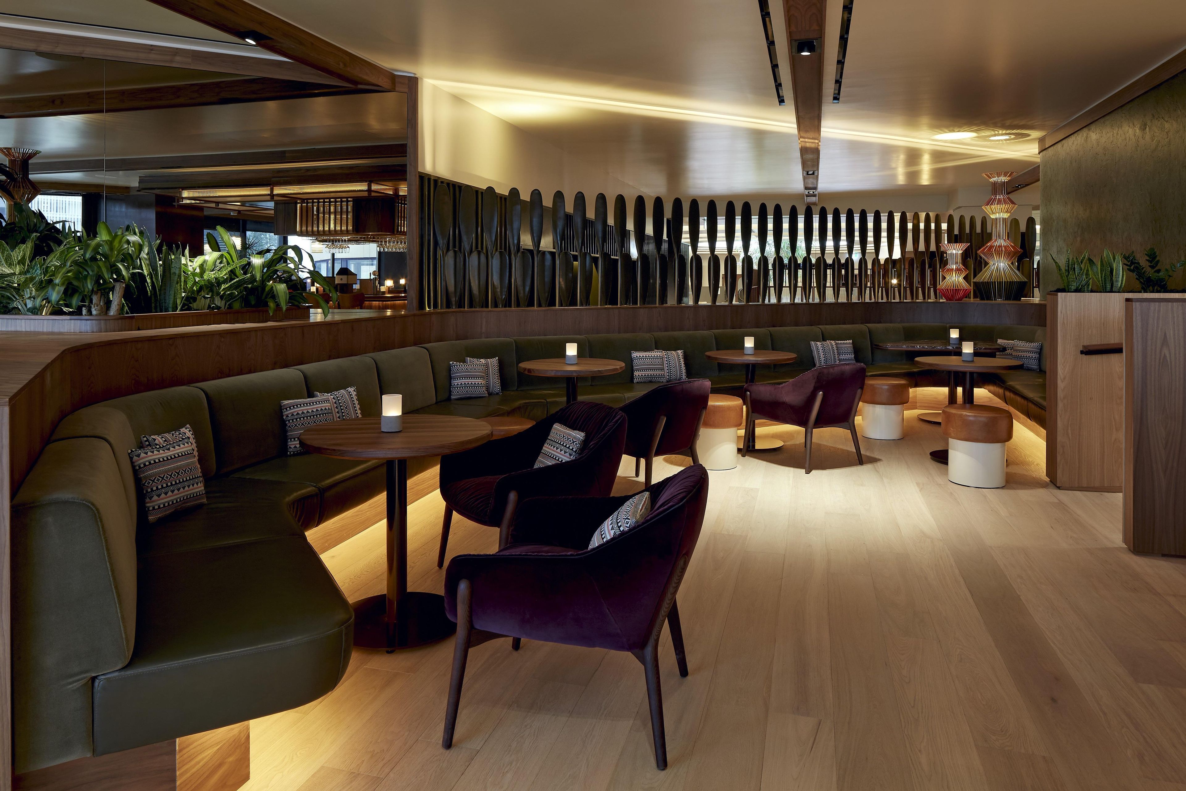 Un interior de restaurante moderno con una barra larga, cabinas y mesas redondas.