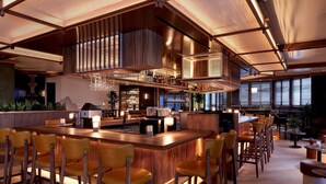 A modern bar area with a long counter, multiple bar stools, and a high ceiling with exposed beams. - DoubleTree by Hilton Montreal (Montreal)